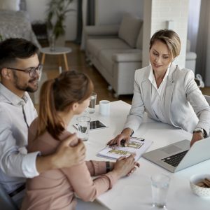 Above view of real state agent and couple using laptop a meeting.