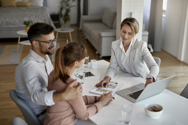 Above view of real state agent and couple using laptop a meeting.